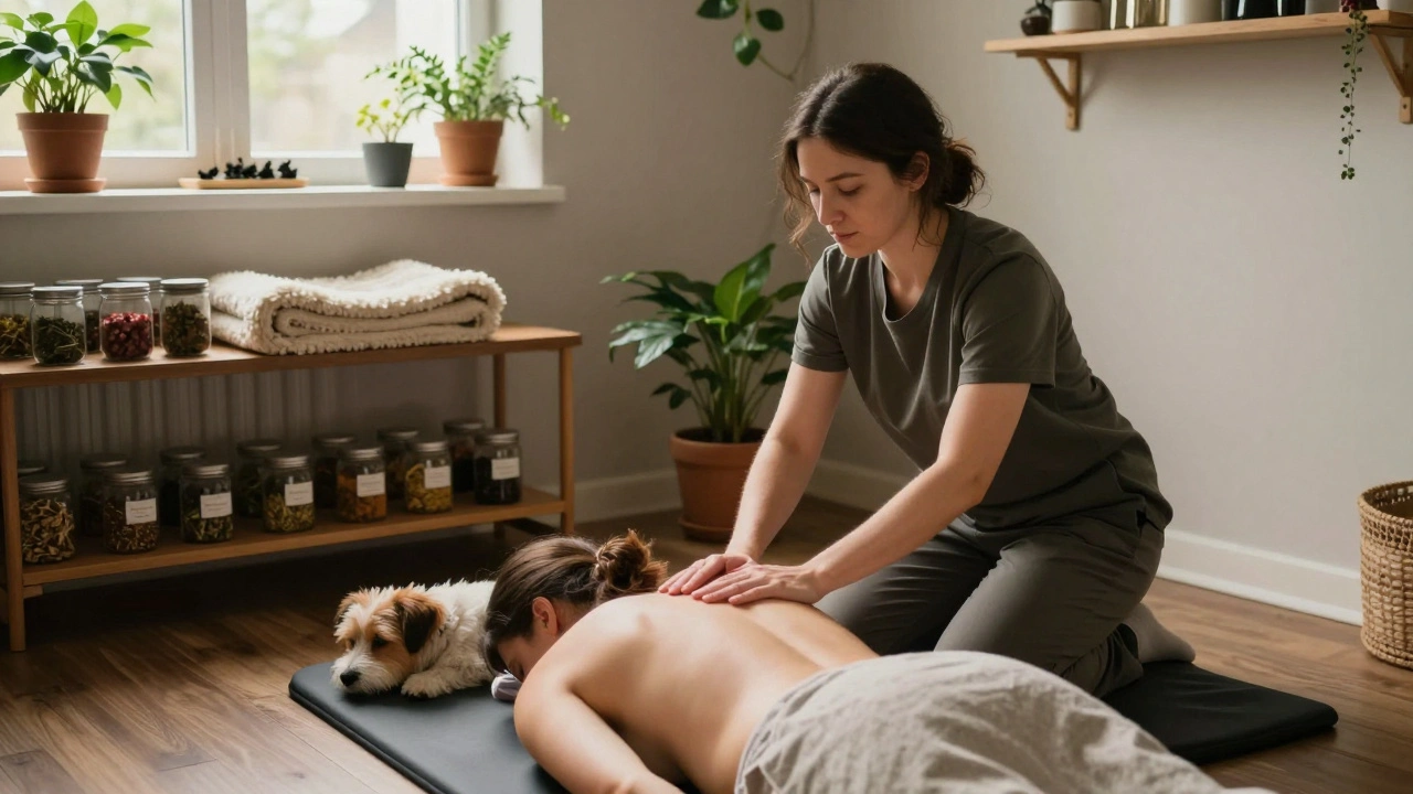 Therapeut masseert iemand op een mat op de vloer in een warme, persoonlijke woonkamer met een hond die naast hen ligt.